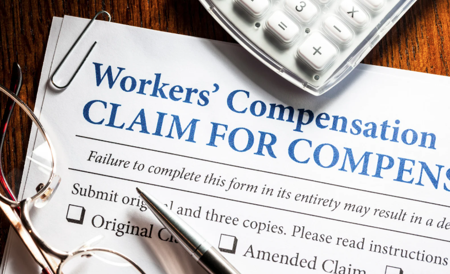 Workplace Injury in Kentucky Claim Form with calculator, glasses, and pen on top.